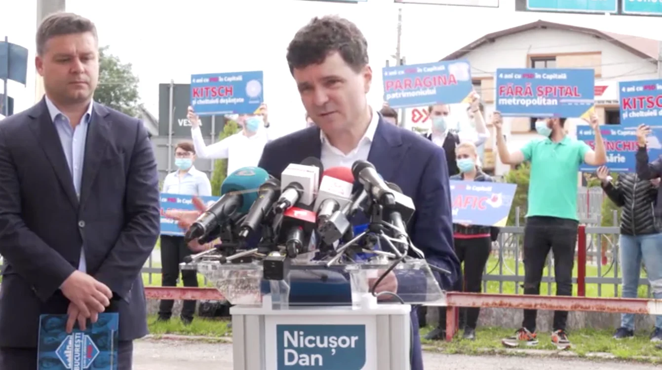 În timp ce Nicușor Dan făcea bilanțul mandatului Firea, în spatele său erau oameni cu pancarte