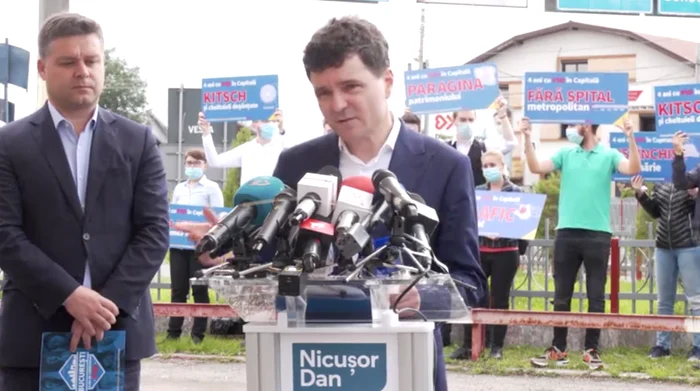 În timp ce Nicușor Dan făcea bilanțul mandatului Firea, în spatele său erau oameni cu pancarte