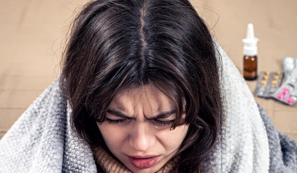 young woman is coughing while sitting home wrapped blanket jpg
