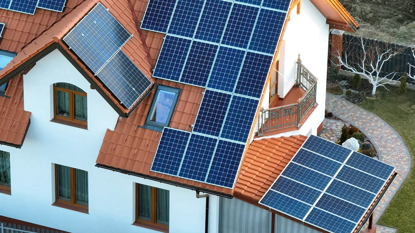 Casă cu acoperișul în mai multe „ape” pe care sunt montate multe panouri fotovoltaice