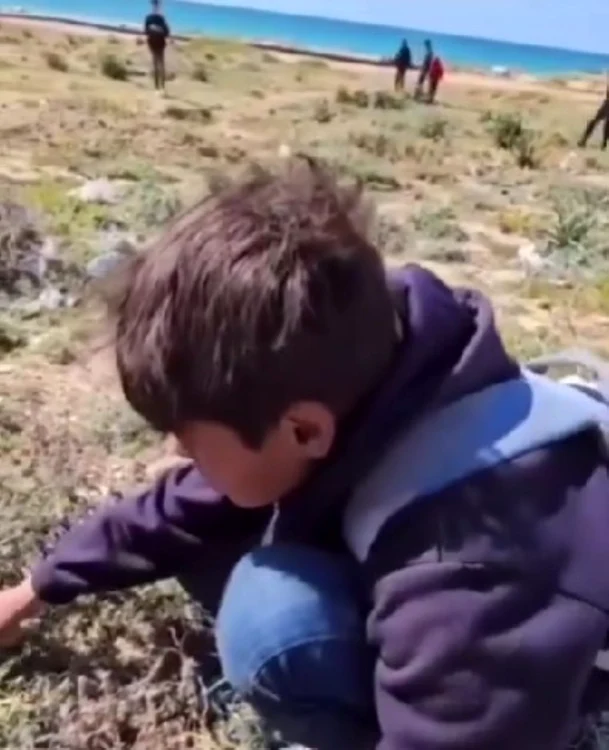 Un copil scormonește în pământ căutând ceva ce poate fi mâncat