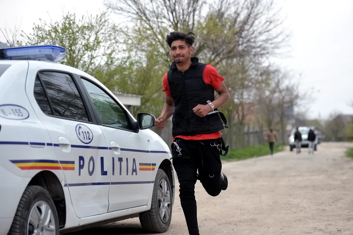 Un tânăr aleargă pe lângă o mașina a Polițieifoto: Mediafax