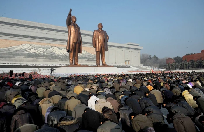 Oameni închinându-se în faţa statuilor lui Kim Ir Ser, preşedintele etern, şi fiul său Kim Jong-il