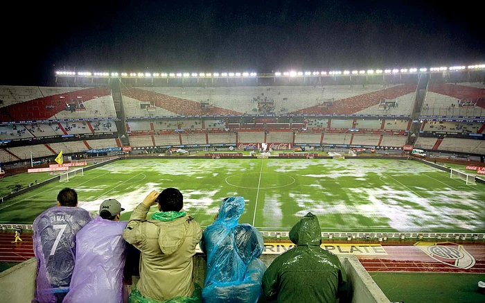 
    Puţinilor spectatori de la  Buenos Aires nu le-a rămas decât  să facă poze cu bălţile de pe terenFoto: AP  