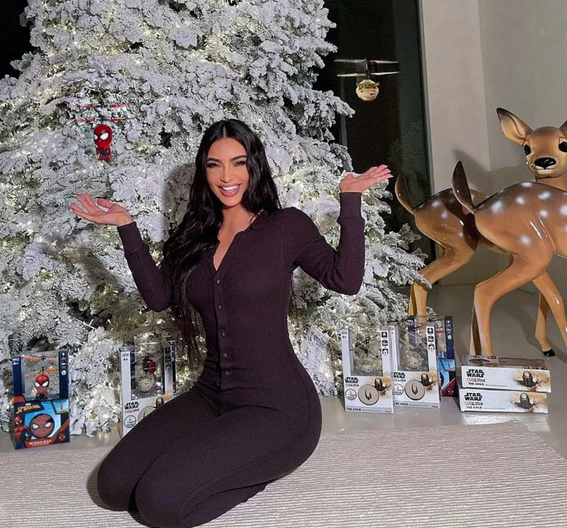 Kim Kardashian, într-o salopetă maro, în fața bradului de Crăciun