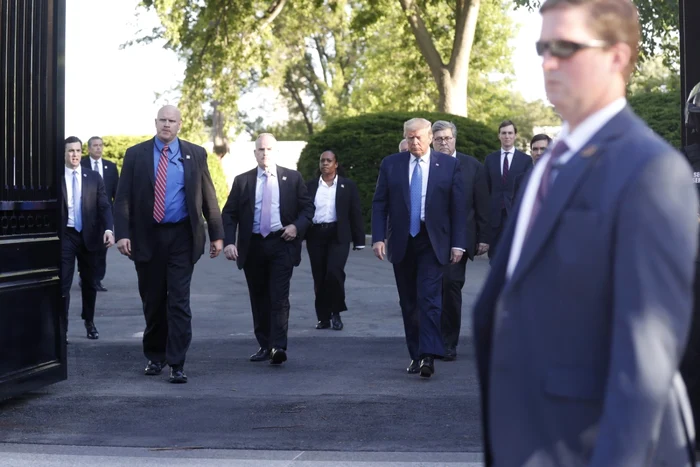 Preşedintele Donald Trump ieşind pe 1 iunie, pe o poartă a Casei Albe, însoţit de oficiali. Foto: FOTO EPA-EFE