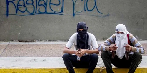 Două persoane stau în timpul unui marş al opoziţiei la Caracas Venezuela FOTO EPA / Miguel Gutierrez