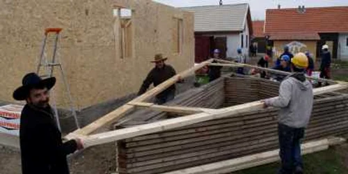 Gabor Ianoș ajută voluntarii la ridicarea locuinței lui