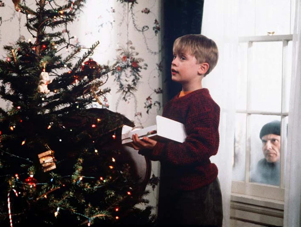 Kevin McCallister este spionat prin fereastră de Harry, în timp ce împodobeşte bradul