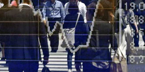 Pietoni se reflectă într-un panou indicator al pieţei bursiere din Tokyo Japonia FOTO EPA / Franck Robichon