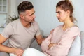 side view attentive man sitting couch calm down his serious girlfriend with crossed arms home jpg