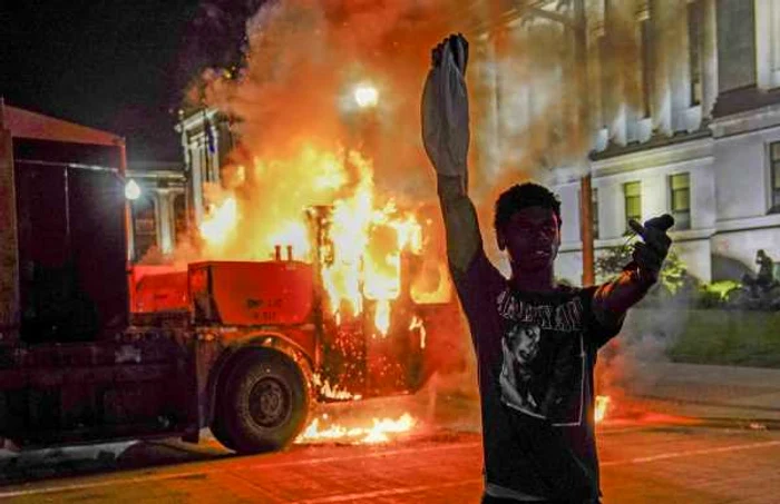Protestatar în faţa unei maşini de gunoi incendiate în Wisconsin după ce un bărbat de culoare a fost împuşcat 24 august 2020 FOTO EPA-EFE