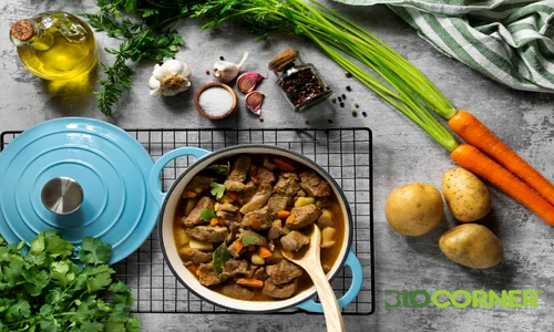 tocanita de carne cu legume gatita intr o oala albastra inconjurata de ingrediente proaspete cartofi morcovi si usturoi biocorner png