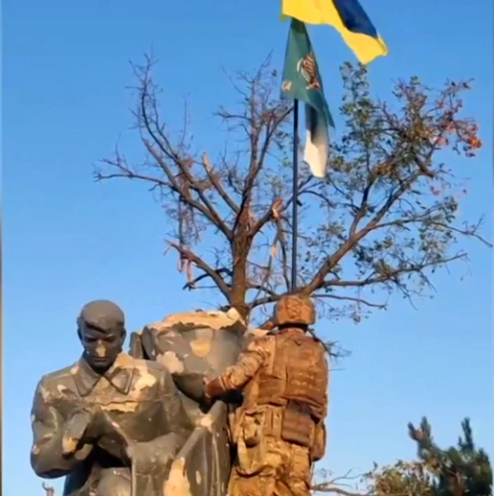 Soldații ucraineani arborând steagul lângă un monument sovietic din satul Urojaine FOTO Captură