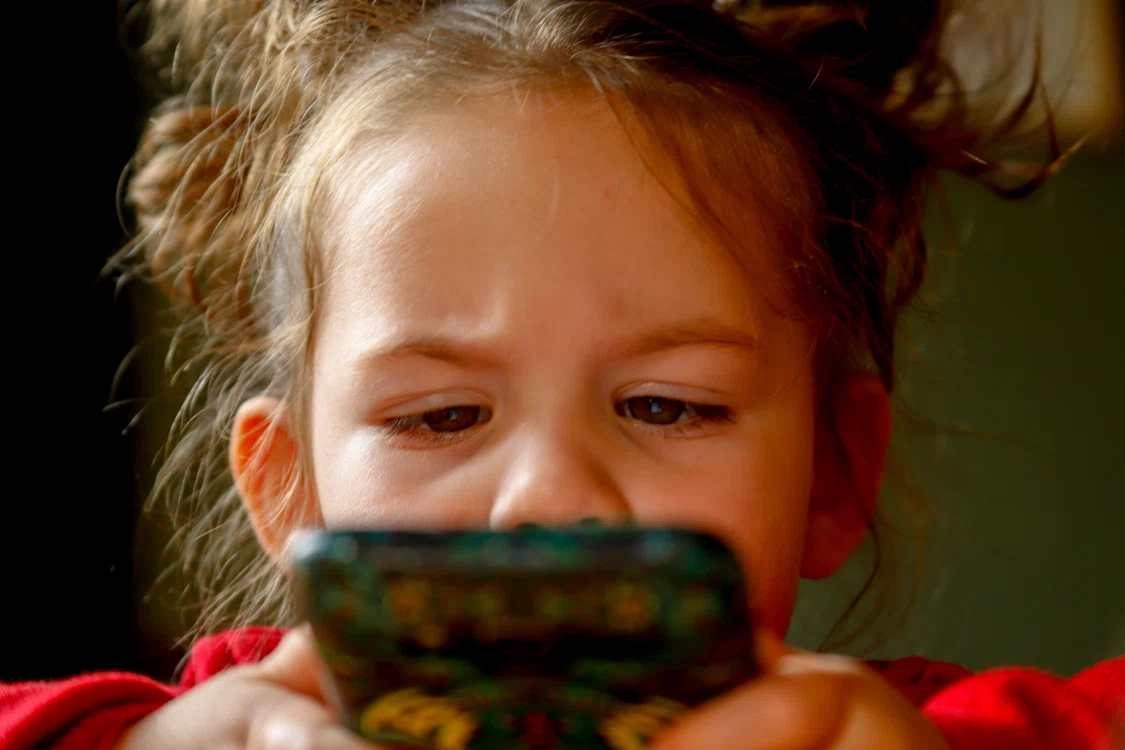 Copil privind încruntat un ecran de telefon. Foto: Pixabay