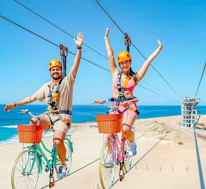 Două persoane pe biciclete, pe tiroliana pentru biciclete din Los Cabos- cea mai lungă din lume