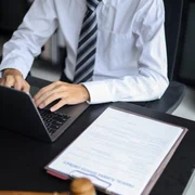 Avocat care lucrează în birou investighează cazul citind documente, folosind laptop-ul și tableta
