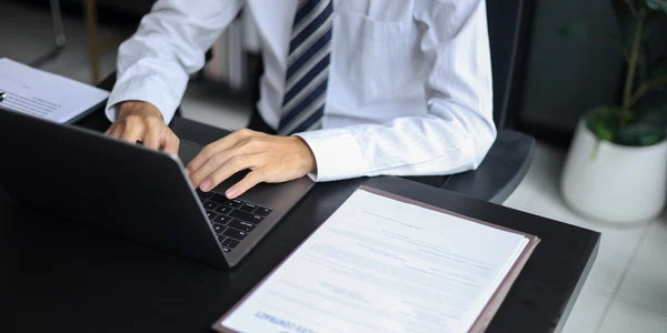 Avocat care lucrează în birou investighează cazul citind documente, folosind laptop-ul și tableta
