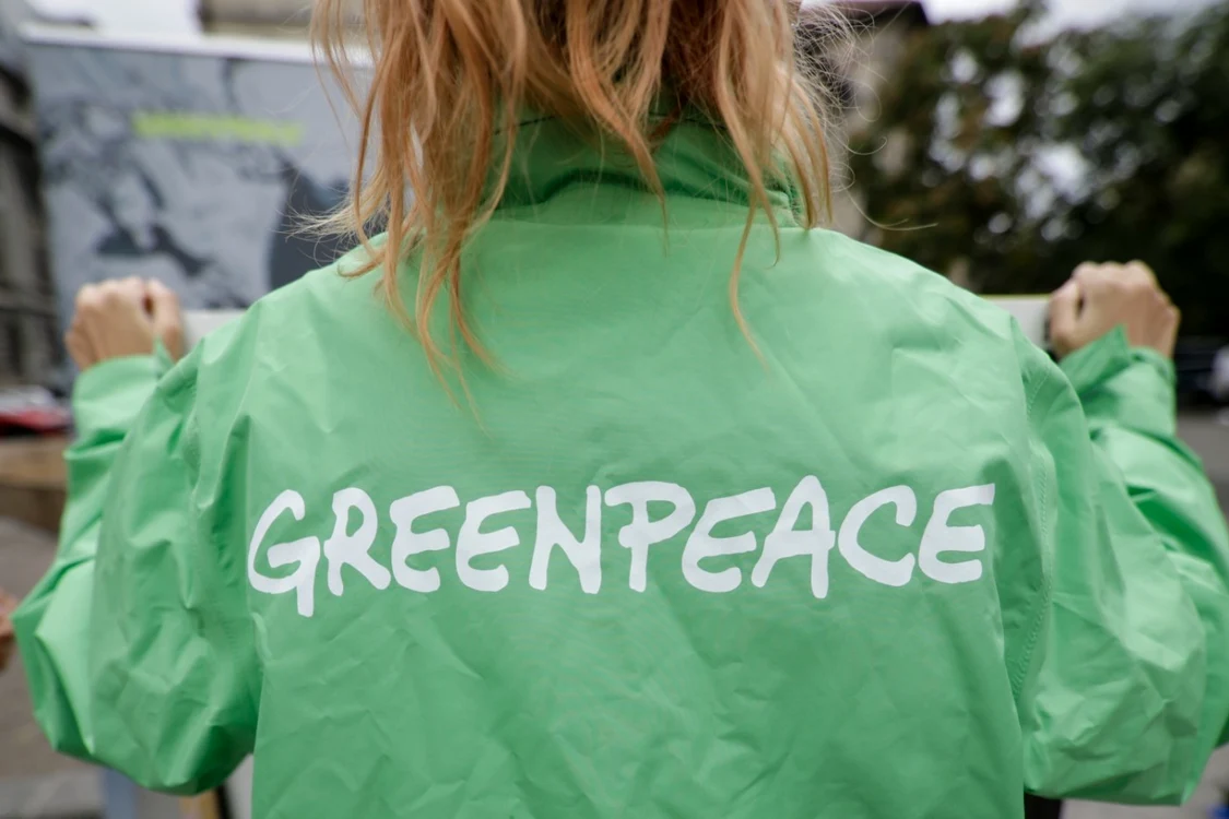 Tânără pe spatele jachetei căreia scrie Greenpeace