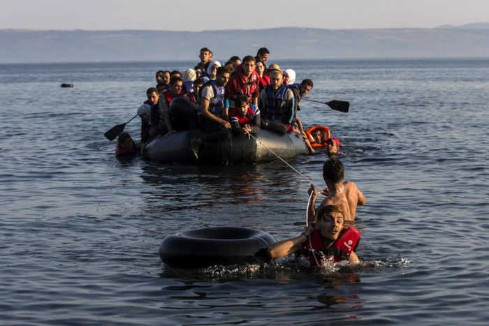 Doi emigranţi trag o ambarcaţiune supraaglomerată cu refugiaţi sirieni şi afgani care sosesc de pe coastele turceşti pe insula grecească Lesbos FOTO AP