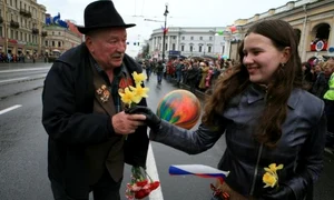 Bătrânul primește flori de la o tânără care venise să urmărească parada jpeg