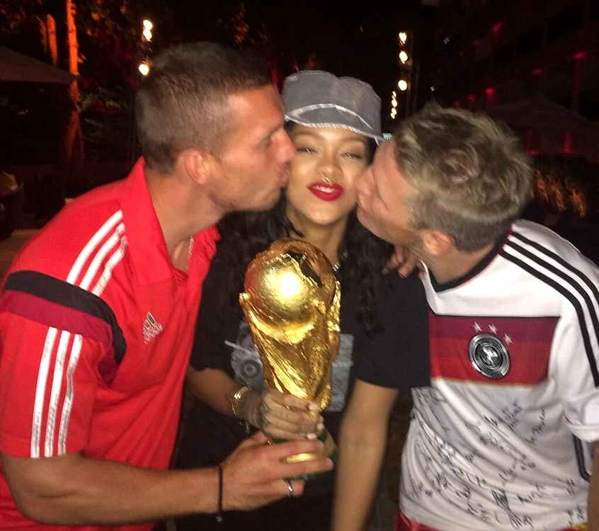 
    Podolski şi Schweinsteiger o sărută cu foc pe cântăreaţa care ţine trofeul Cupei Mondiale  