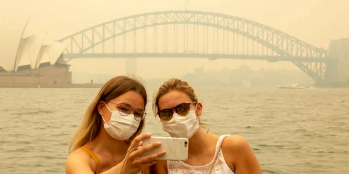 Turistele nemţoaice Julia Wasmiller (S) şi Jessica Pryor îşi fac un selfie pe Mrs Macquaries chair purtând măşti din cauza fumului puternic la Sydney Australia FOTO Guliver / Getty Images / Jenny Evans