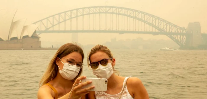 Turiste din Germania purtând măşti din cauza fumului puternic la Sydney FOTO Guliver/ Getty Images/ Jenny Evans