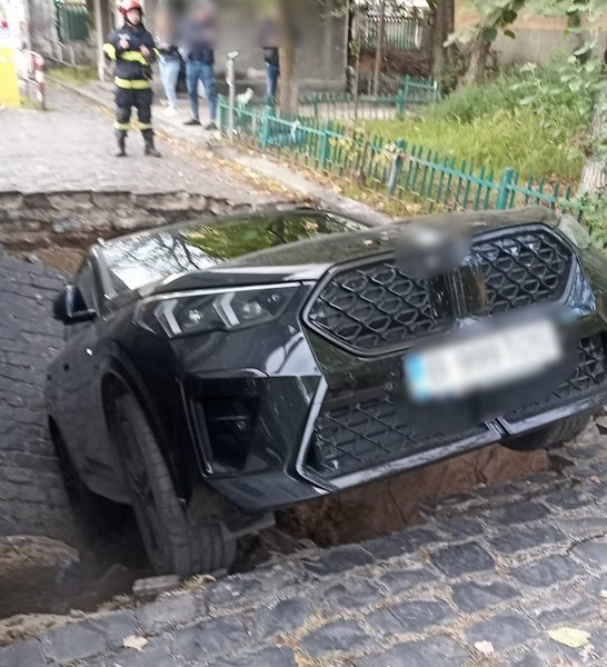 Mașina înghițită de o stradă surpată în București, scoasă din groapă