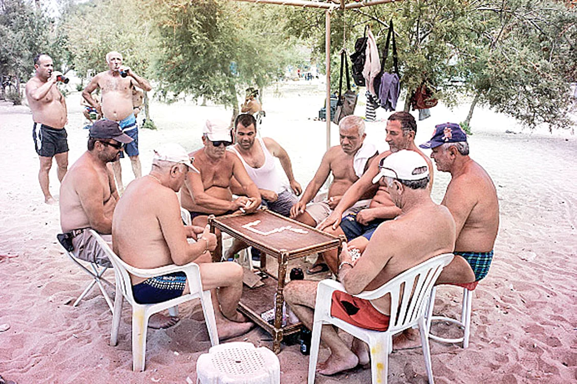 Grecii stau la plajă şi joacă table  fără nici o grijă