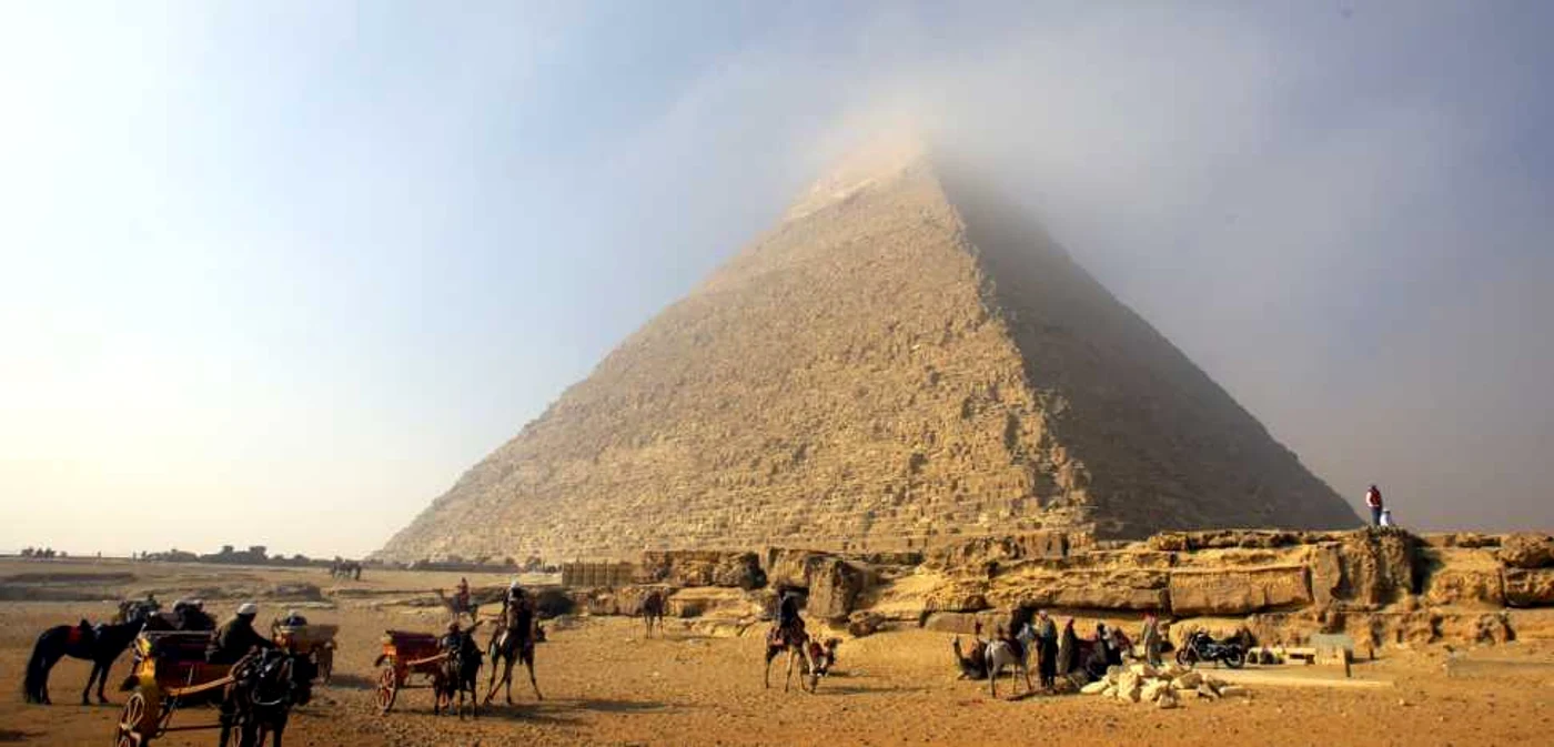 Oameni pe cămile aşteaptă turişti în timp ce un nor ceţos acoperă vârful Piramidei lui Cheops (Khufu) cea mai mare dintre cele trei piramide din Giza la periferia sudică a oraşului Cairo Egipt FOTO EPA – EFE / Khaled Elfiqi