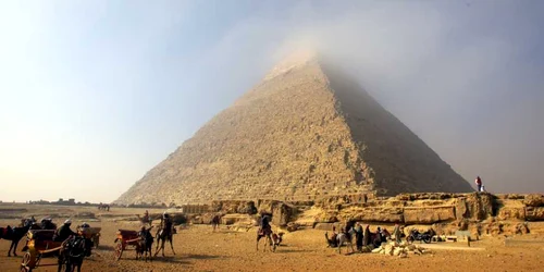 Oameni pe cămile aşteaptă turişti în timp ce un nor ceţos acoperă vârful Piramidei lui Cheops (Khufu) cea mai mare dintre cele trei piramide din Giza la periferia sudică a oraşului Cairo Egipt FOTO EPA – EFE / Khaled Elfiqi