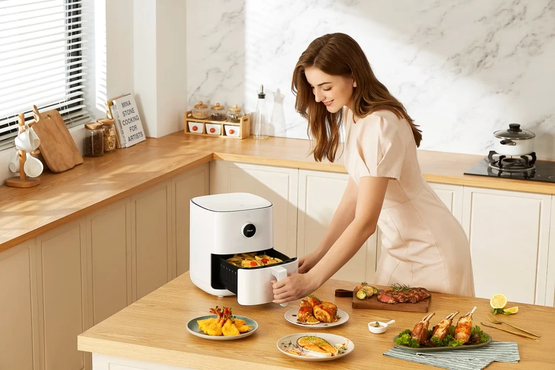 Femeie care prepară carne, pește și alte alimente la un air fryer