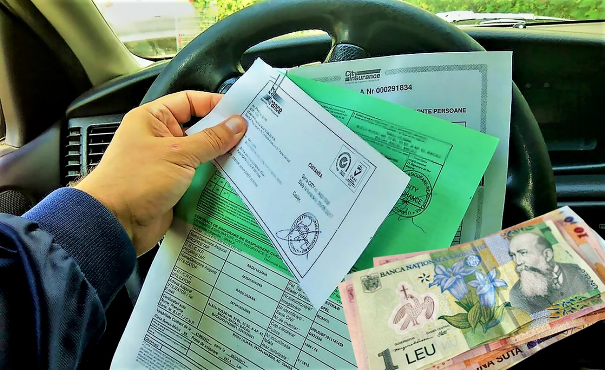 Cineva ține cu o mână asigurarea RCA deasupra volanului