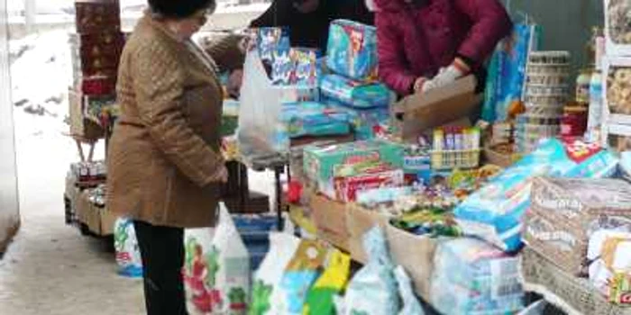 O clientă cântăreşte oferta de detergenţi a unei vânzătoare din Bazar