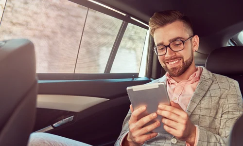 smiling successful stylish young businessman gray suit pink shirt using tablet riding back seat luxury car jpg