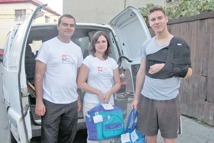 Andrei şi Laura, în tricouri albe, inscripţionate cu numele micii lor firme, îi dau pachetul studentului Mihai Bodolan
