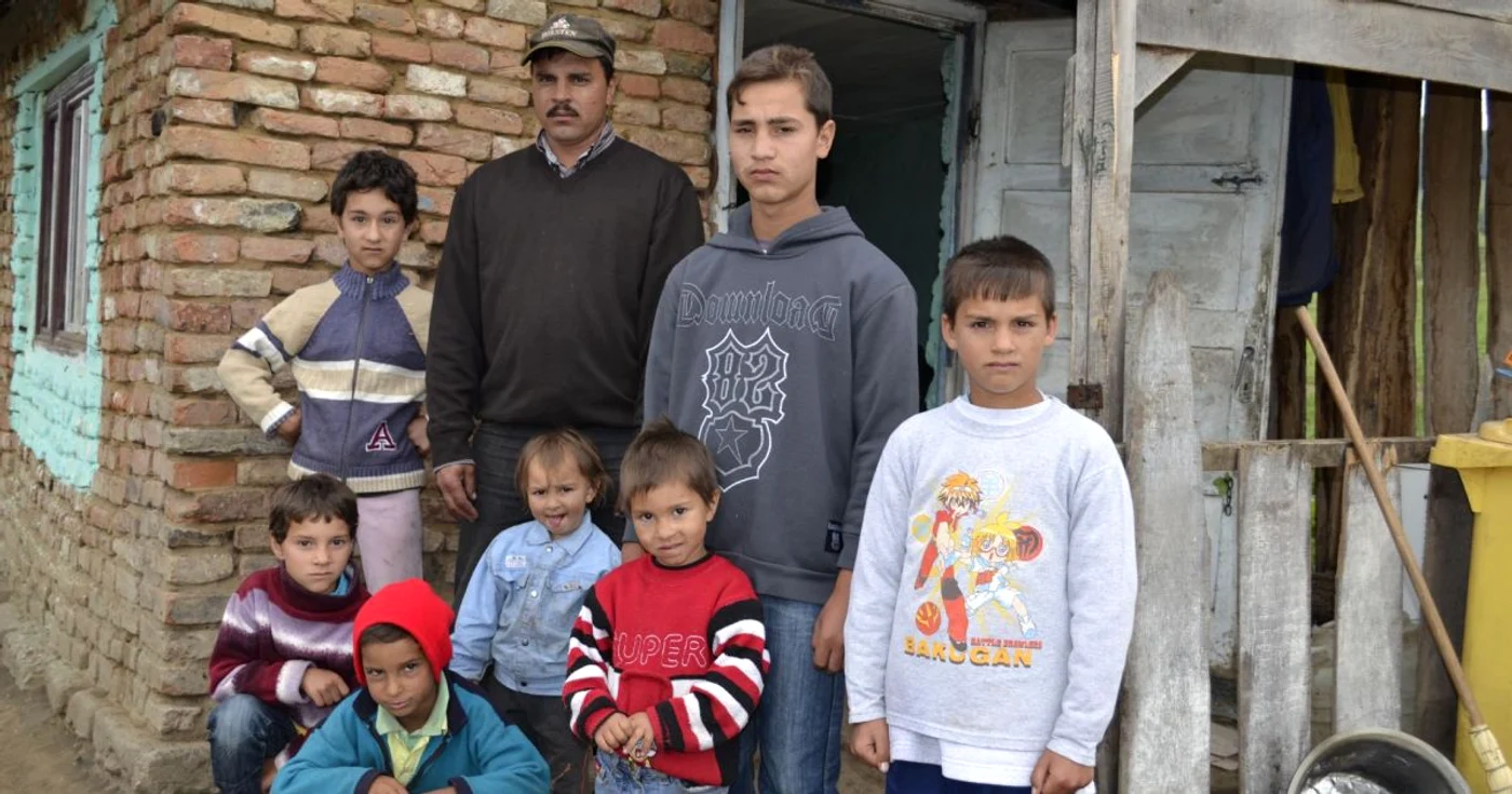 Cei 7 copii si tatal lor in fata casei modeste