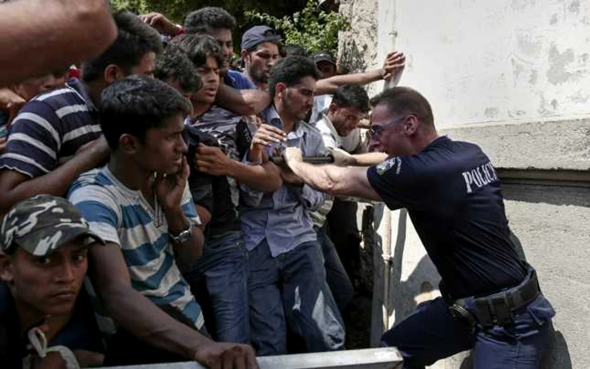 Un poliţist încearcă să ţină mai mulţi migranţi la rând pentru procedura 
de  înregistrare la o secţie de poliţie de pe Insula Kos FOTO AP