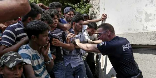 Un poliţist încearcă să ţină emigranţii la rând pentru procedura de  înregistrare la o secţie de poliţie de pe insula Kos Grecia FOTO AP