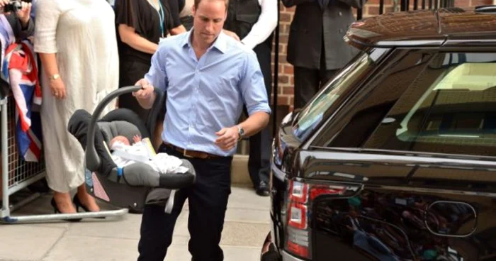 Prinţul William, devenit tătic pe 22 iulie, purtându-şi bebeluşul în scaunul auto special către maşină FOTO AFP