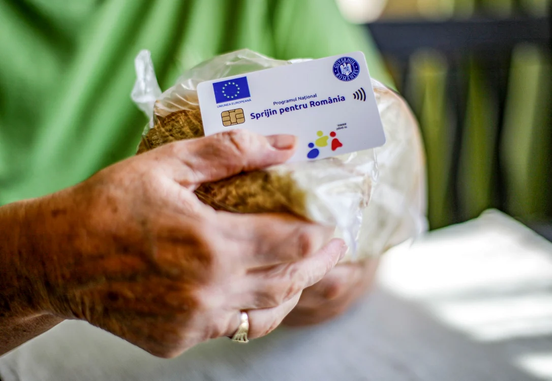 Un vârstnic ține în mână cardul social