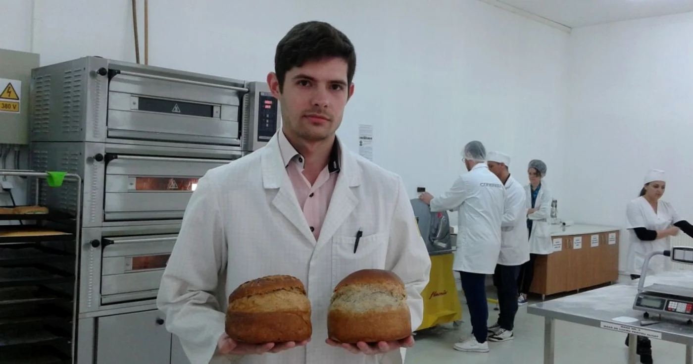 Iulian Rusu ţine în mâini două pâini din făină de cânepă. În spate este cuptorul care le-a copt FOTO: Florina Pop