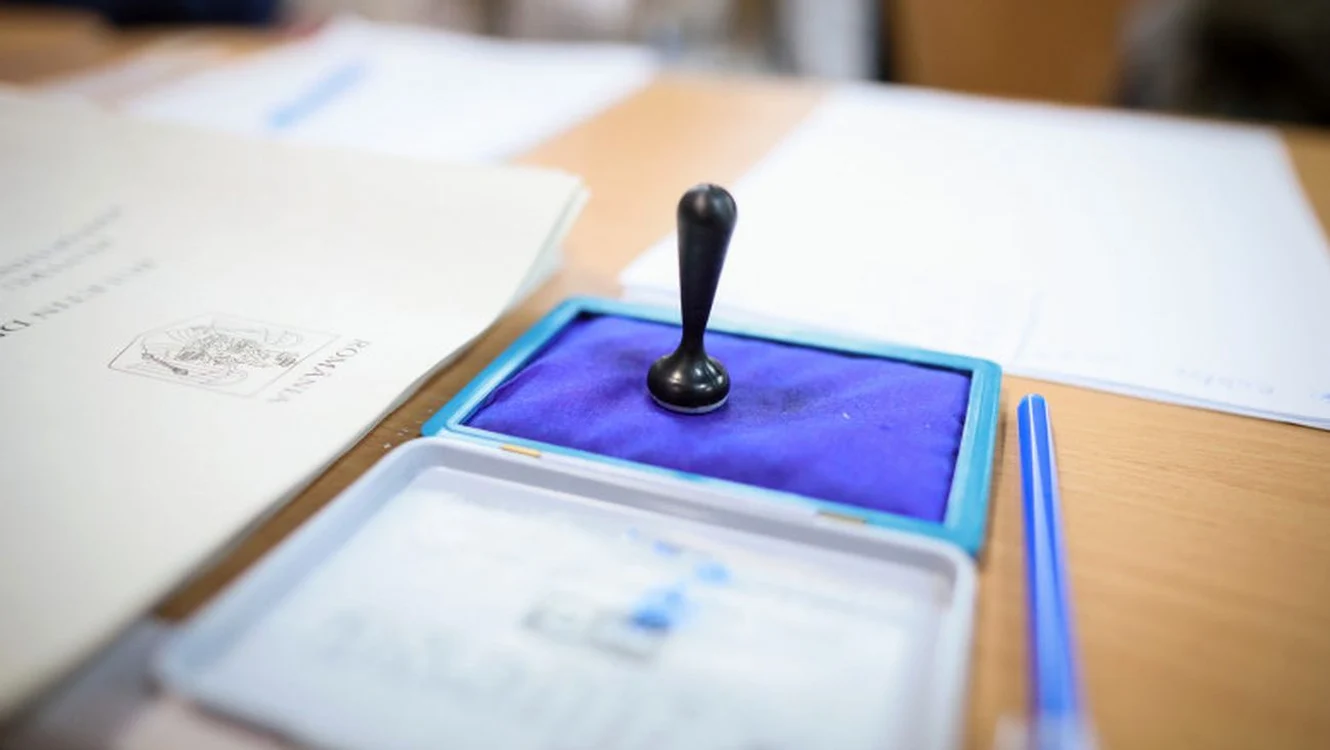 O ștampilă de vot pusă pe tușieră lângă buletinele de vot dintr-o secție de votare