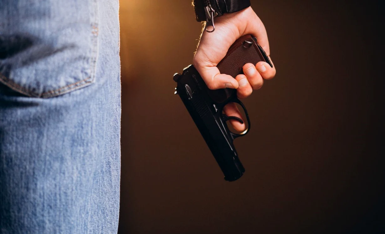 Un bărbat ține un pistol negru în mână