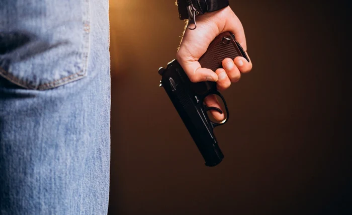 Un bărbat ține un pistol negru în mână