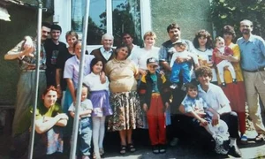 Smiley în copilărie, îmbrăcat în pantaloni roșii, tricou, geacă sport, cu papuci și șapcă, alături de bunica lui și de familie jpeg