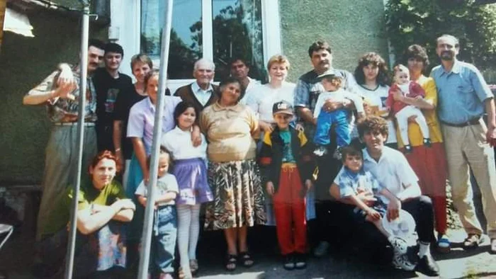 Smiley în copilărie, îmbrăcat în pantaloni roșii, tricou, geacă sport, cu papuci și șapcă, alături de bunica lui și de familie