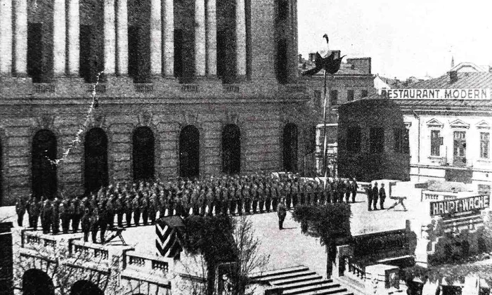 Paradă militară germană în faţa Casei Armatei (Cercul Militar). Redenumită Haupt-Wache, clădirea e în timpul ocupaţiei sediul corpului central de gardă al Comenduirii armatei germane. În fundal, Restaurantul Modern