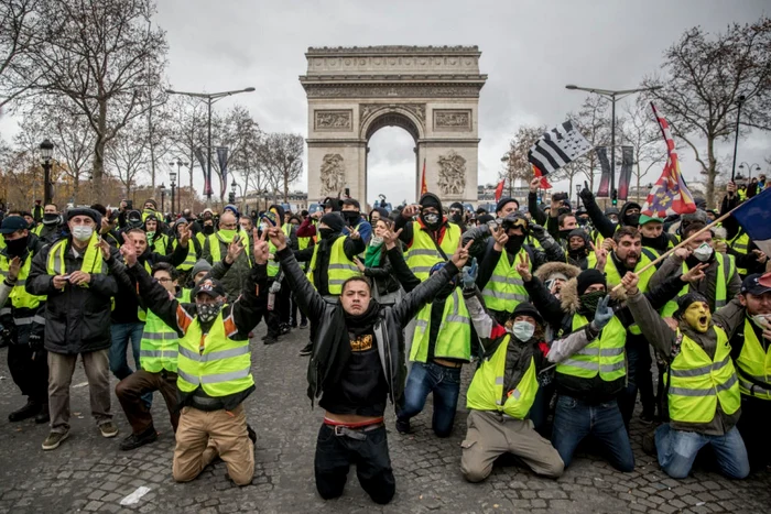 Manifestanţii cântă în timpul protestului vestelor galbene pe 
Champs-Elysées lângă Arcul de Triumf de la Paris FOTO Guliver / 
Getty Images / Chris McGrath